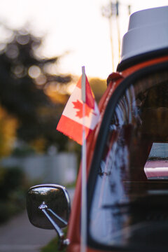 A small Canada flag is attached to a orange camper van.