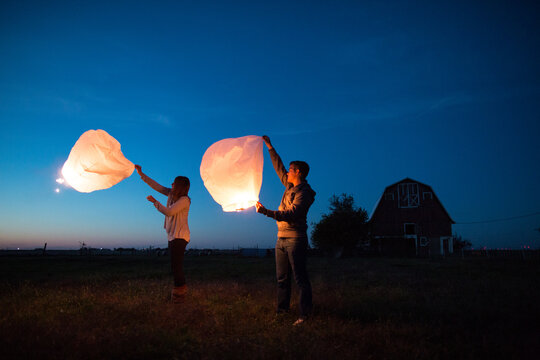 young couple lighting Chinese lanterns at twilight