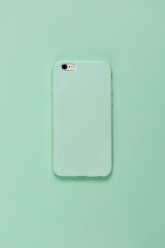 Rear sight of mobile phone with mint cover on mint background