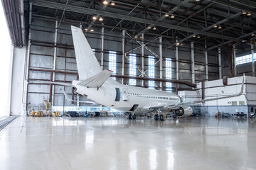 White passenger airplane in the hangar. Airplane under maintenance. Checking mechanical systems for flight operations - obrazy, fototapety, plakaty
