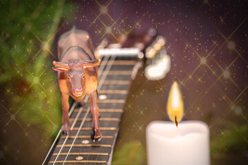 New Year's Eve. The bull toy stands on the guitar necklace. The white candle is burning. Selective trick.