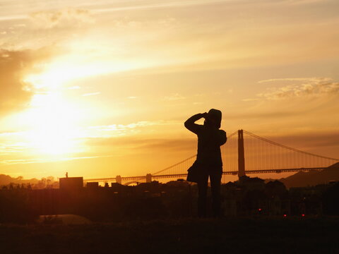 Person photographing Golden Gate Bridge at sunset