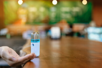 Alcohol nano mist sprayer for hand cleaning to prevent the spread of the Corona virus (Covid-19) to serve customers at coffee shop. Modern health technology. New normal lifestyle. Selective focus
