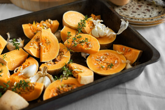 Butternut squash,smoked garlic and thyme in a roasting tin,ready to be cooked.
