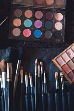 A palette of colourful eye shadows and brushes