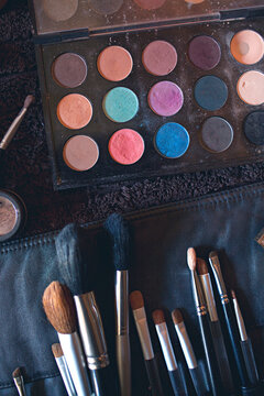 A palette of colourful eye shadows and brushes