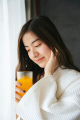 Asian woman drinking healthy fresh orange juice.
