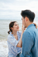 Obraz premium Asian couple traveler looking at each other eyes on the beach.