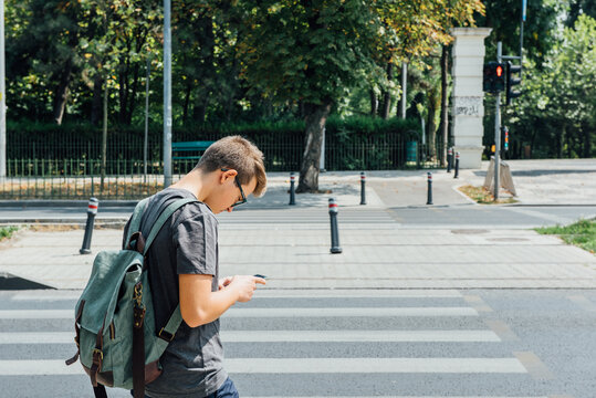 Teenager playing location-based augmented reality game on his smartphone not paying attention to the traffic