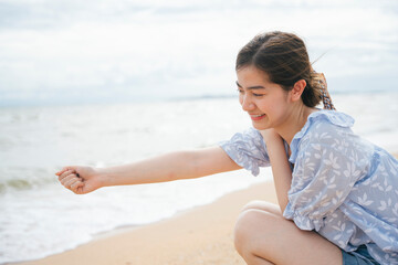 Fototapeta na wymiar Asian woman grab a pile of sand on the beach.
