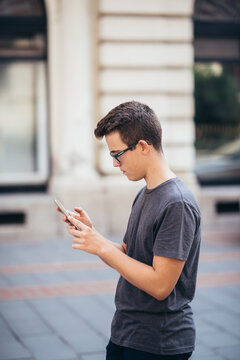 Teenager playing location-based augmented reality game on his smartphone in the city