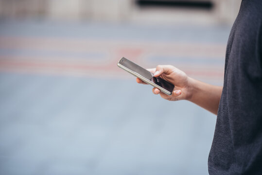 Teenager playing location-based augmented reality game on his smartphone in the city
