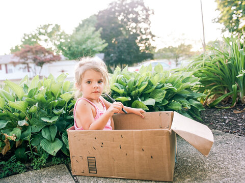 little girl sits in cardboard box