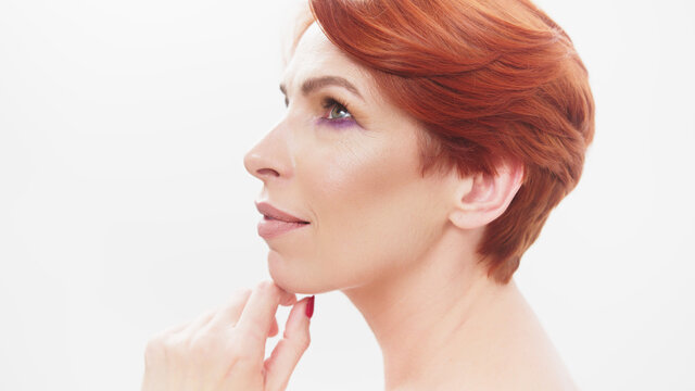 Redhead woman in her 40s posing against white background. Beauty shot. High quality photo