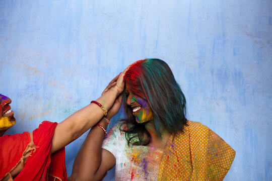 Indian woman giving spray color to other wonam