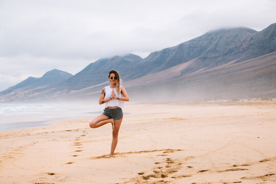 Woman doing a yoga posture on a paradisiac beach