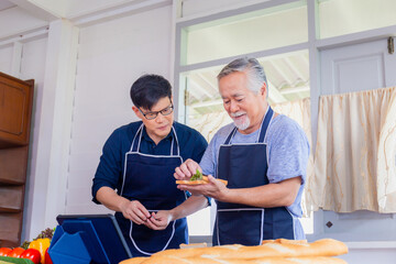 Cheerful senior asian father and middle aged son cooking together at kitchen, Happiness asian family concepts