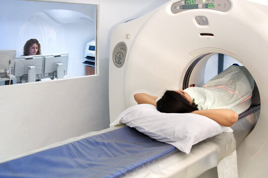 Female technician watching from the control room a patient getting a CT scan