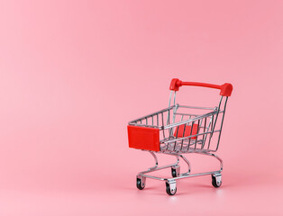 empty shopping cart on pink background with copy space.