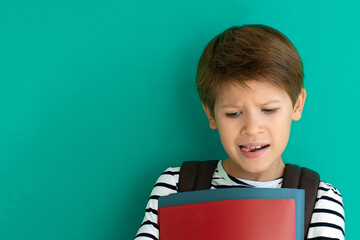Schoolboy with a bored face with copy space. Pupil with a backpack and textbooks. Back to school