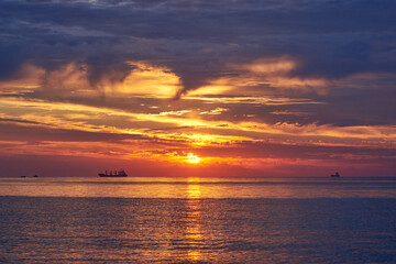 Sunset on the sea, ships standing on the horizon.