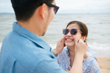 Romantic couple traveler wearing sunglasses touching each other cheeks on the beach.