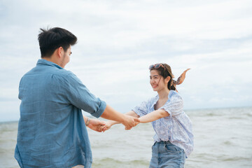 Happy romantic asian couple traveler holding hands dance on the beach.