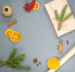 gift in craft paper with an orange, cinnamon and a sprig of spruce, flatly, copy space.