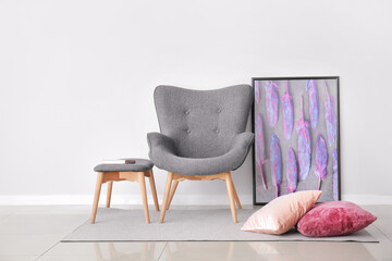 Stylish armchair and ottoman near light wall in room
