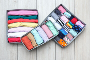 Organizers with clean clothes on wooden floor
