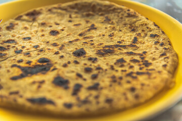 Selective focus view of traditional Indian food Aloo paratha or potato stuffed flat bread over colourful or wooden background. This is popular breakfast dish in north India tourist destination.