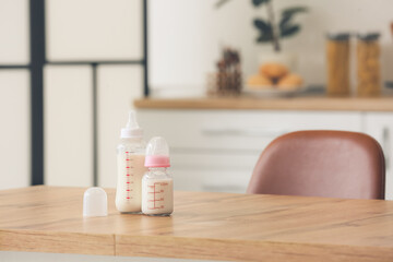 Bottles of milk for baby on table in kitchen