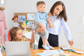 Working mother with naughty little children in atelier