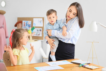 Working mother with naughty little children in atelier