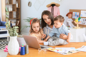 Fototapeta premium Working mother with naughty little children in atelier