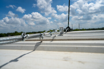 steel cable connect with lightning rod on rooftop above metal sheet in cloudy blue sky day stock...