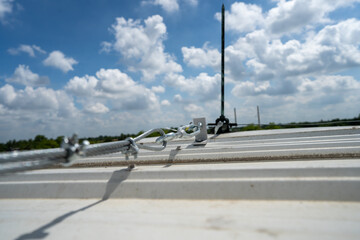 steel cable connect with lightning rod on rooftop above metal sheet in cloudy blue sky day stock photo