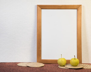 Portrait empty wooden frame mockup with yellow apples. White background. Scandinavian interior, home design. Art concept.