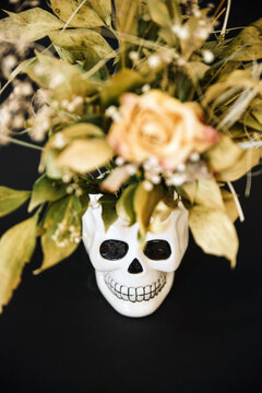 close up of a Ceramic skull with dried flowers on a black background,