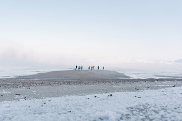 the tide is out on a frosty day in the winter on the North sea and people have come out on a bare bottom covered with ice