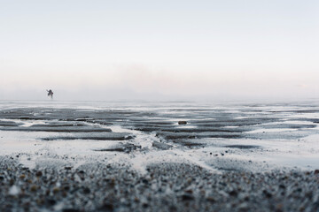the tide is out on a frosty day in the winter on the North sea and people have come out on a bare bottom covered with ice