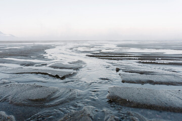 the low tide in the North sea in winter on a frosty day exposed the bottom with sand and ice