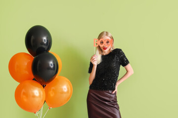 Beautiful young woman with balloons on color background. Halloween celebration