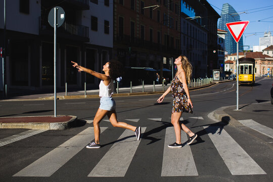 Cheerful girls crossing the road at a zebra crossing