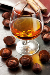 Glass of whiskey, chocolate truffles   and  cigar on  dark  table