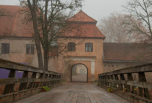 The restored old Shlokenbek manor in Latvia. View of the Arch from the river bank on a foggy autumn morning