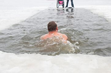 a man in winter in frost extreme swimming at -20, in ice water swims in an ice-hole
