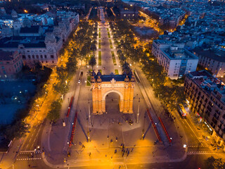 Aerial view of Barcelona cityscape with illuminated Arc de Triomf on central avenue at twilight, Spain