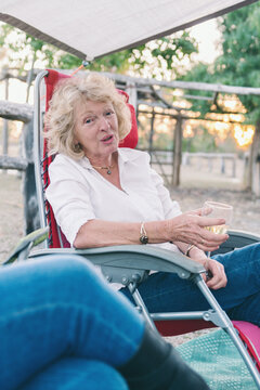 happy retiree chatting as she sits outdoors on a camping trip, w