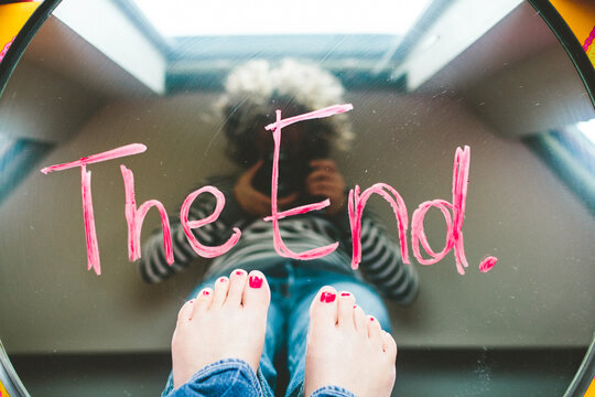 Reflection of woman taking a photo in a mirror with the words ""The End"".